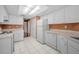Functional kitchen with white appliances, cabinets, and a tile floor, plus a view to the living area at 2010 Groveland Rd, Palm Harbor, FL 34683