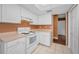 Functional kitchen with white appliances, cabinets, and a tile floor, plus a view to the living area at 2010 Groveland Rd, Palm Harbor, FL 34683