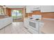 Bright kitchen features white cabinets and appliances and sliding glass doors to the backyard patio at 2010 Groveland Rd, Palm Harbor, FL 34683