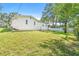 Spacious backyard features healthy grass, mature trees, a white fence and a short retaining wall at 2017 Rebecca Dr, Clearwater, FL 33764