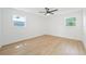 Bright bedroom with a ceiling fan and two windows allowing natural light to fill the room with light-colored wood floors at 2017 Rebecca Dr, Clearwater, FL 33764
