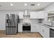 The layout of the kitchen shows stainless steel appliances, updated white cabinetry, and quartz countertops at 2333 Indigo Dr, Clearwater, FL 33763