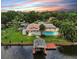 Waterfront home featuring a private pool, dock, and lush landscaping against a colorful sunset backdrop at 2401 Roberta Ln, Clearwater, FL 33764