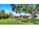 Charming single-story home with a well-manicured lawn, red-trimmed windows, and mature trees at 2401 Roberta Ln, Clearwater, FL 33764
