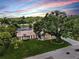 Beautiful home exterior features a large front yard, mature trees, and a screened-in pool at 2401 Roberta Ln, Clearwater, FL 33764