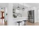 Bright, white kitchen featuring stainless steel appliances, modern light fixtures, and an island with bar stools at 2401 Roberta Ln, Clearwater, FL 33764