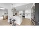 Open kitchen with white cabinetry, stainless steel appliances, island with seating, and modern pendant lights at 2401 Roberta Ln, Clearwater, FL 33764