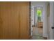 Hallway view featuring wood-paneled closet doors, hardwood floors, and an open doorway to a sunlit room at 2412 W Prospect Rd, Tampa, FL 33629