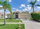Well-maintained home with a tidy front yard, palm trees, and a two-car garage at 24811 Gun Smoke Dr, Land O Lakes, FL 34639
