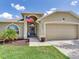 Welcoming home front with a well manicured lawn, an American flag, and a two car garage at 24811 Gun Smoke Dr, Land O Lakes, FL 34639