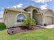 Beautifully landscaped front yard with an arched entryway, palm trees, and a two car garage at 24811 Gun Smoke Dr, Land O Lakes, FL 34639