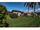 Exterior shot of a home featuring a tile roof, arched window, lush landscaping, and green lawn at 2691 Saddlewood Ln, Palm Harbor, FL 34685