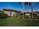 Exterior shot of a home featuring a tile roof, arched window, lush landscaping, and green lawn at 2691 Saddlewood Ln, Palm Harbor, FL 34685