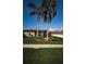 Exterior shot of a home featuring a tile roof, arched window, lush landscaping, and green lawn at 2691 Saddlewood Ln, Palm Harbor, FL 34685