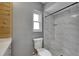 Bathroom featuring a tiled shower, gray walls, white toilet and a bright window at 2914 Forest Cir, Seffner, FL 33584