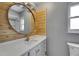 Bright bathroom featuring a round mirror, cedar accent wall, and a modern white vanity at 2914 Forest Cir, Seffner, FL 33584