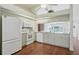Modern kitchen with white appliances and cabinets, hardwood floors and view to breakfast nook at 38237 Eucalyptus Dr, Zephyrhills, FL 33542