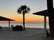 Serene beach scene with sunset, featuring seating and a palm tree silhouette at 4712 Marine Pkwy # 203, New Port Richey, FL 34652