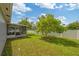 Spacious backyard with green lawn, a mature tree, and an enclosed screened patio at 602 Hillpoint Way, Brandon, FL 33510