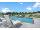 A clear swimming pool is surrounded by lounge seating and a black metal fence under a blue sky with clouds at 6206 64Th N Way, Pinellas Park, FL 33781