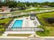 Aerial view of a community pool area with lounge chairs, umbrellas, and a nearby pond at 6206 64Th N Way, Pinellas Park, FL 33781