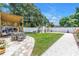 Landscaped backyard features a covered patio, manicured lawn, a white fence, and stone walkways at 650 63Rd S Ave, St Petersburg, FL 33705