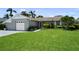 Charming single-story home with a well-manicured lawn and tropical landscaping, and a gray brick facade at 8718 Tahiti Ln, Tampa, FL 33615