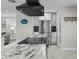 Island cooktop with granite countertop, black range hood, and stainless steel refrigerator in a renovated kitchen at 8718 Tahiti Ln, Tampa, FL 33615