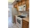 Kitchen area with white appliances, wood cabinets, and tile flooring at 8801 Orange Blossom Dr, Seminole, FL 33772
