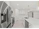 Bright kitchen features stainless steel appliances, white cabinetry, and a large center island with quartz countertop at 9073 Fruitland Ave, Englewood, FL 34224