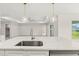 Open kitchen boasts a large island with sink, quartz countertops, and pendant lighting, connecting to living area at 9073 Fruitland Ave, Englewood, FL 34224