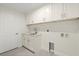 Bright laundry room featuring white cabinetry, sink and tile flooring at 9073 Fruitland Ave, Englewood, FL 34224