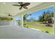 Covered patio with ceiling fans overlooks the expansive backyard and well-manicured lawn at 9073 Fruitland Ave, Englewood, FL 34224