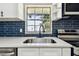 Close-up of kitchen with modern faucet, quartz countertops, stainless appliances and navy subway tile backsplash at 9312 N Tampa St, Tampa, FL 33612