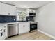 Modern kitchen showcasing stainless steel appliances, white cabinetry, quartz countertops, and stylish navy backsplash at 9312 N Tampa St, Tampa, FL 33612
