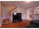 Open-concept living area with stairs, hardwood floors, and modern television at 10819 Lake Saint Charles Blvd, Riverview, FL 33578