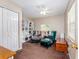 Carpeted bedroom features a large built-in bookcase, ceiling fan, and an armchair with ottoman at 11704 Orange Grove Ter, Riverview, FL 33569