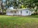 Inviting single-story home featuring a covered porch and mature trees in a green yard at 11704 Orange Grove Ter, Riverview, FL 33569