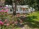 A picturesque single-story home with a charming front porch, flowering shrub and lush landscaping at 11704 Orange Grove Ter, Riverview, FL 33569