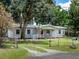 This home has mature landscaping, a gated driveway, and a red front door at 11704 Orange Grove Ter, Riverview, FL 33569