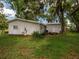 Rear view of the house with green grass and trees providing shade at 11704 Orange Grove Ter, Riverview, FL 33569