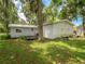 Back exterior view shows the house with a metal roof and leafy trees at 11704 Orange Grove Ter, Riverview, FL 33569