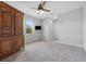 Spacious carpeted bedroom features ceiling fan, large armoire and mounted television at 12121 Rustic River Way, Tampa, FL 33635