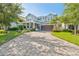 Charming two-story home boasts a paver driveway, manicured lawn, and vibrant landscaping at 12121 Rustic River Way, Tampa, FL 33635