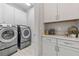 Modern laundry room with front load washer and dryer and white shaker cabinets at 12121 Rustic River Way, Tampa, FL 33635