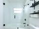 Bathroom with a glass-enclosed tub and shower, white tile, and black hardware at 1317 S Betty Ln, Clearwater, FL 33756