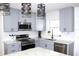 Beautiful kitchen with gray cabinets, stainless steel appliances, tiled backsplash, and decorative lighting at 1317 S Betty Ln, Clearwater, FL 33756