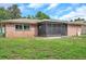 View of brick home with screened lanai and well-manicured lawn, ideal for Gathering gatherings at 1363 Cottage Grove Rd, Tarpon Springs, FL 34689