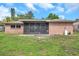 This brick home features a screened lanai, blending indoor/outdoor living spaces with views of a lush backyard at 1363 Cottage Grove Rd, Tarpon Springs, FL 34689