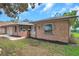 View of the front right side of the house with the yard, exterior brick and an entrance with a small porch at 1363 Cottage Grove Rd, Tarpon Springs, FL 34689